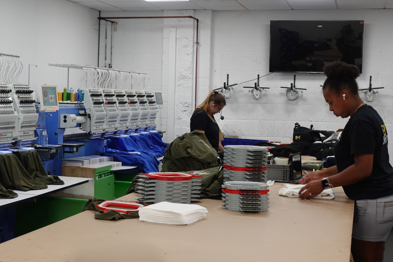 The Penguin Uniform decoration floor in use, with embroidery machines running and the team working alongside them