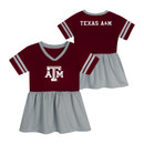 Outerstuff toddler Texas A&M dress featuring a maroon jersey-style top with white A&M logo, gray V-neck and sleeve stripes, gathered gray skirt, and Texas A&M lettering on the back.