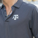 Antigua dark Texas A&M polo featuring an allover small geometric print, classic collared neckline, short sleeves, and an embroidered white A&M logo on the chest for a polished Aggie look.
