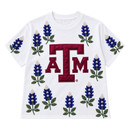 Brianna Cannon Texas A&M white shirt featuring a large maroon A&M logo surrounded by bluebonnet designs embellished with blue and white beads and green beaded leaves across the front and sleeves.