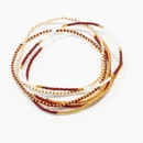 A Wink of Yellow set of six thin beaded bracelets featuring assorted maroon, white, and metallic gold seed bead patterns, displayed together as a coordinated layered bracelet stack.