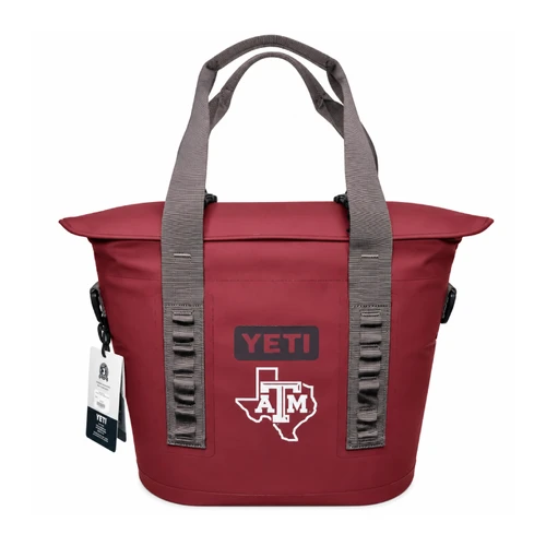 Maroon YETI Hopper soft-sided cooler with gray carrying straps, wide top opening, black YETI logo, and white Texas-shaped A&M emblem on the front. Back features an additional carrying handle.