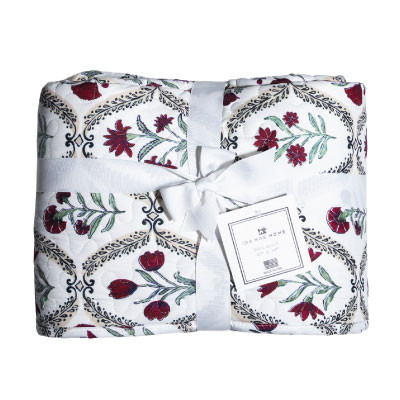 Ida Mae twin size quilt featuring a white background with maroon and red floral patterns, green leafy accents, decorative black details, and a soft quilted design tied with a white ribbon.
