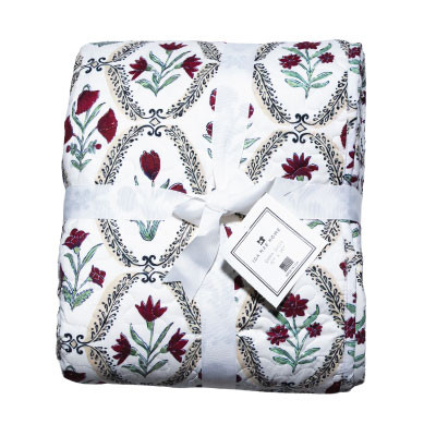 Ida Mae full/queen size quilt featuring maroon and red floral patterns, green botanical accents, decorative black detailing, and a white background, folded and tied with a white ribbon.