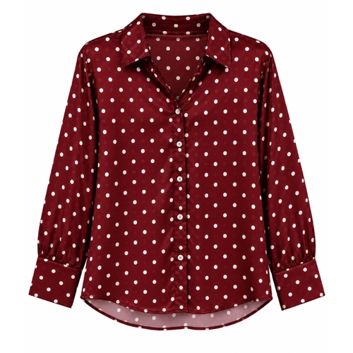 Maroon long sleeve blouse featuring an allover white polka dot pattern, pointed collar, button-front closure, wide cuffs, relaxed silhouette, and curved shirttail hem.