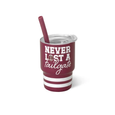 Swig Mini Shot Cup featuring a maroon design with white “Never Lost a Tailgate” lettering, white stripes around the base, a clear lid, and coordinating maroon reusable straw.