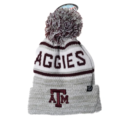 Gray and maroon Zephyr Texas A&M knit beanie featuring “Aggies” lettering, an embroidered ATM logo, striped detailing, and a multicolor pom on top, styled as a cozy cold weather game day hat.