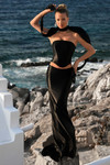 Model wearing Portia and Scarlett PS26114 black liquid jersey two-piece prom dress with strapless corset top, column skirt, and coordinating neck scarf