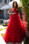 Model wearing the red ruffled ballgown outdoors, showcasing the volume and movement of the skirt.