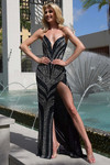 Model wearing black/silver Jasz Couture 7941 with strapless V-neckline, beaded patterning, and thigh-high slit.