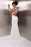 Back view of the white gown highlighting the crisscross straps and dramatic lace train.