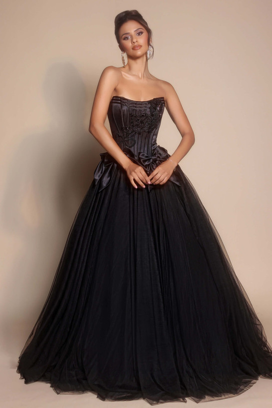 Model wearing Portia and Scarlett PS26102 black satin bow ballgown with strapless corset bodice and voluminous tulle skirt