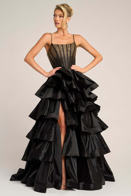 Model wearing Portia and Scarlett PS26253 black and gold ruffled ball gown with beaded corset bodice and thigh-high slit.