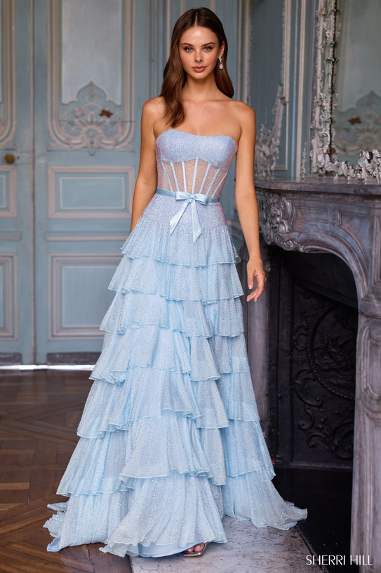Sherri Hill 57739 in Light Blue with sheer stone embellished corset bodice, dainty bow, and cascading ruffle tiers.