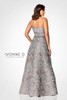 Back view highlights structured pleats and full A-line flare in luminous silver brocade