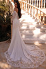 Demetrios 8259 fit-and-flare featuring scalloped lace train on marble staircase, back view