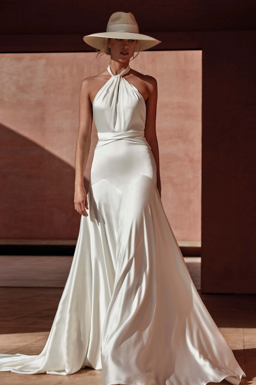 This halter-style wedding gown stuns with its gathered neckline, sleek satin fabric, and flowing A-line skirt This halter-style wedding gown stuns with its gathered neckline, sleek satin fabric, and flowing A-line skirt