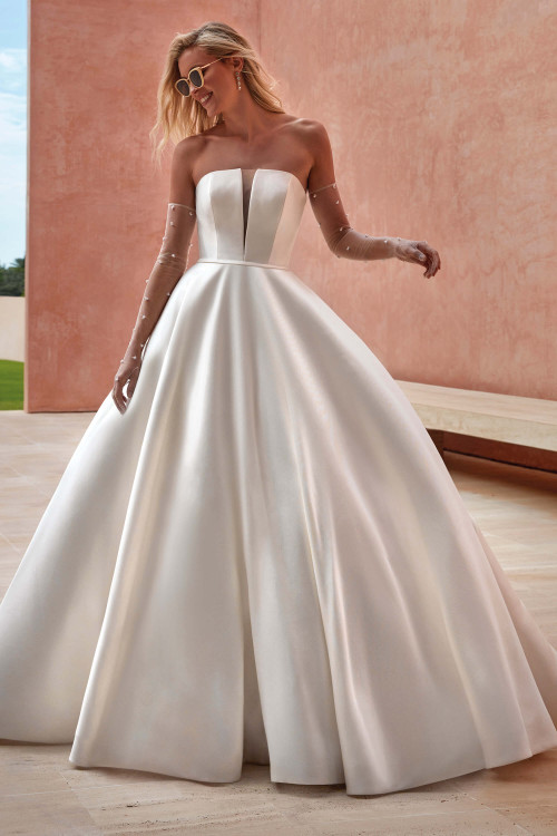 This strapless ball gown shines with a structured bodice featuring a plunging sheer panel and a full, flowing skirt This strapless ball gown shines with a structured bodice featuring a plunging sheer panel and a full, flowing skirt
