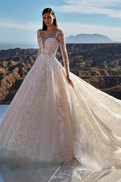 This breathtaking gown features intricate lace with beaded long sleeves and a flowing ball gown silhouette This breathtaking gown features intricate lace with beaded long sleeves and a flowing ball gown silhouette