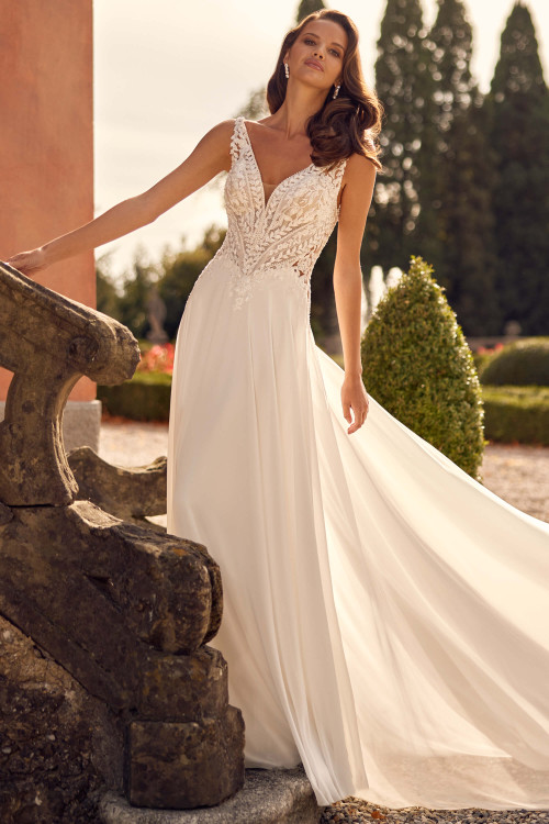 Romantic A-line gown with a plunging lace bodice and flowing chiffon skirt. Romantic A-line gown with a plunging lace bodice and flowing chiffon skirt.