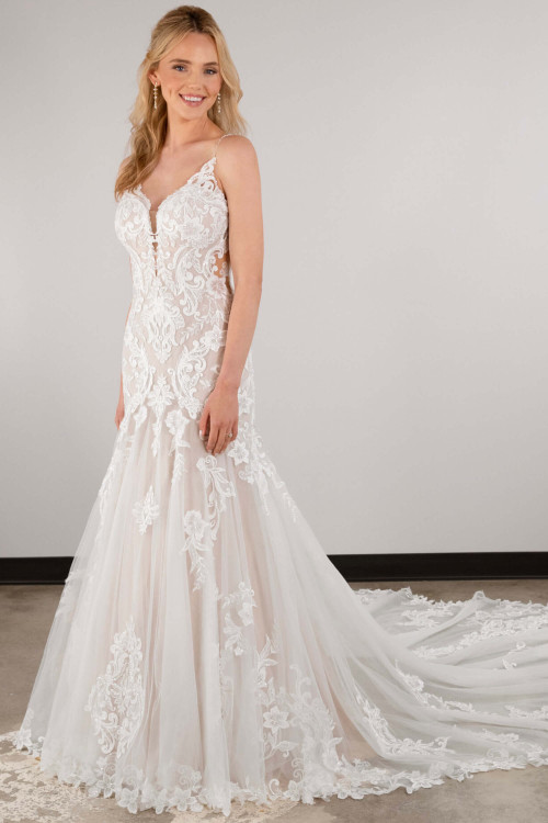 Ethereal lace appliqués dance over a sheer, fitted silhouette with a dramatic tulle train Ethereal lace appliqués dance over a sheer, fitted silhouette with a dramatic tulle train