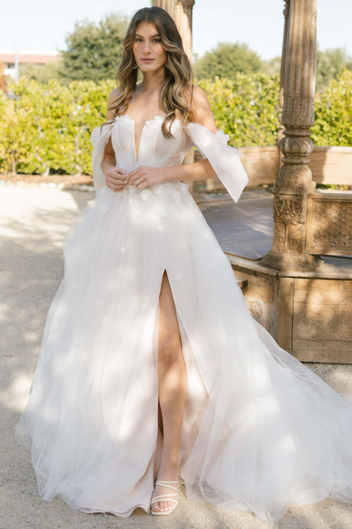 Whimsical tulle gown features floral appliqués, off-shoulder ties, and a daring front slit Whimsical tulle gown features floral appliqués, off-shoulder ties, and a daring front slit