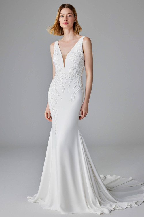 Sleek crepe gown with deep V-neckline and shimmering beadwork cascading down the bodice Sleek crepe gown with deep V-neckline and shimmering beadwork cascading down the bodice