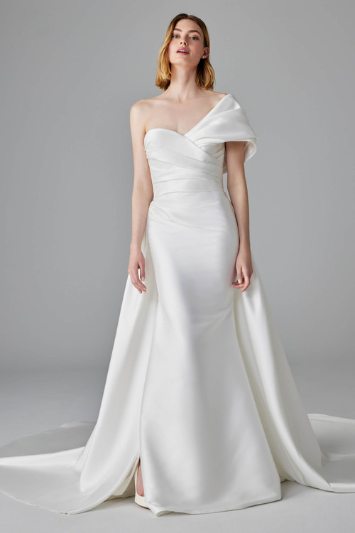 Chic one-shoulder gown with asymmetrical draping, detachable train, and a sleek fit-to-flare silhouette Chic one-shoulder gown with asymmetrical draping, detachable train, and a sleek fit-to-flare silhouette