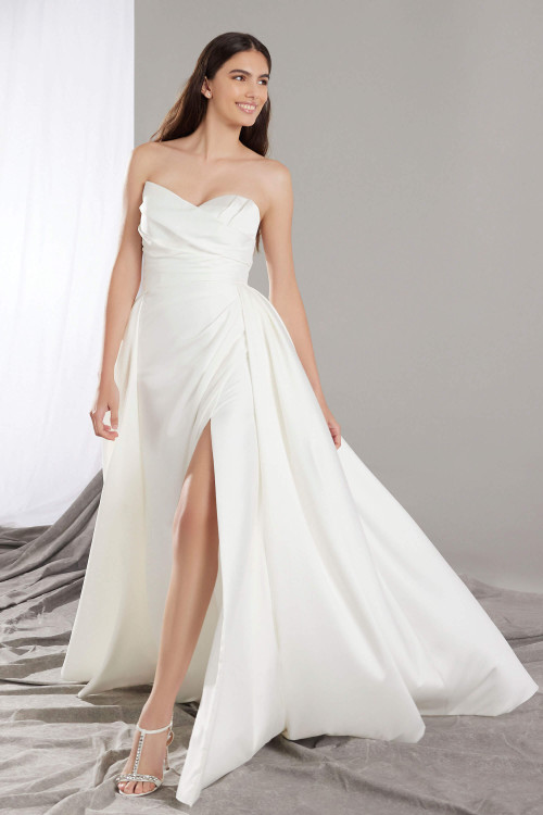 Soft Mikado gown with and asymmetrical pleated bodice, high slit, and full overskirt for dramatic flair Soft Mikado gown with and asymmetrical pleated bodice, high slit, and full overskirt for dramatic flair