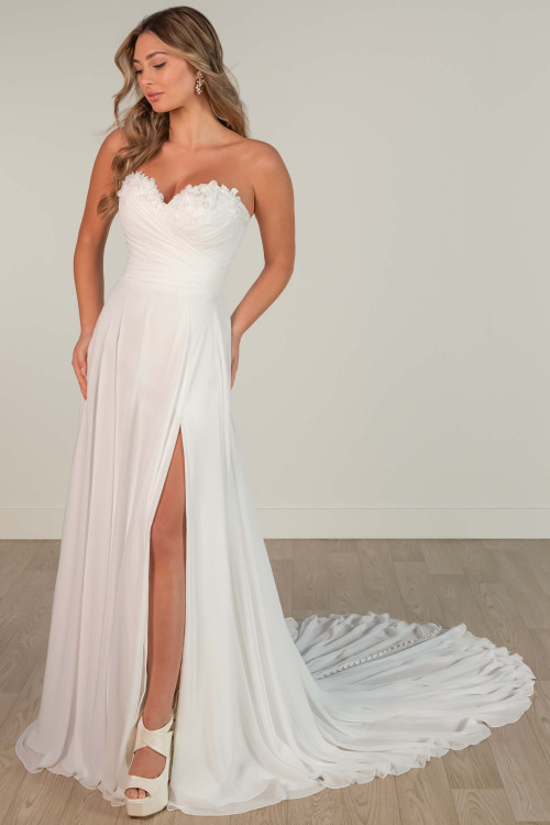 Strapless chiffon wedding gown with ruched bodice, floral neckline, and thigh-high slit. Strapless chiffon wedding gown with ruched bodice, floral neckline, and thigh-high slit.