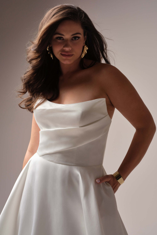 Close-up of the Radiance gown's bodice, showcasing the architectural, asymmetrical folded strapless neckline in lustrous satin.