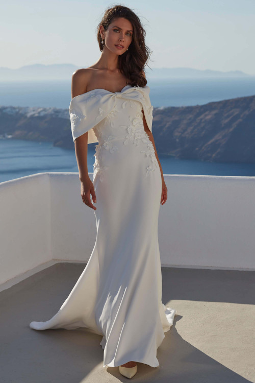 Front view of Femi by Madison James with detachable bow bodice and crepe sheath silhouette. Front view of Femi by Madison James with detachable bow bodice and crepe sheath silhouette.