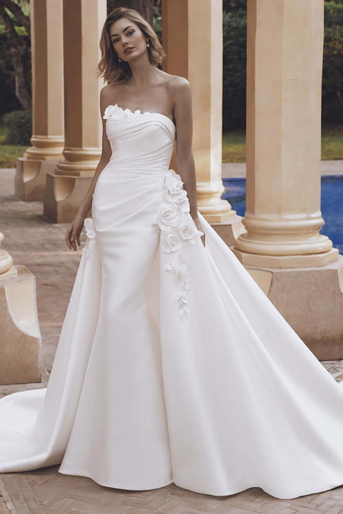 Bride in Enzoani Udelia mermaid gown with strapless sculpted neckline and 3D floral details. Bride in Enzoani Udelia mermaid gown with strapless sculpted neckline and 3D floral details.