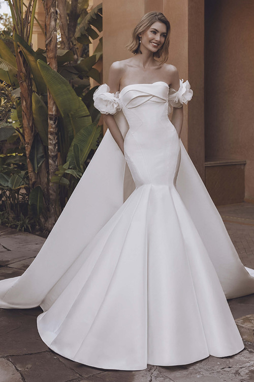 Bride in Umara gown showing sleek Mikado silhouette with detachable cape. Bride in Umara gown showing sleek Mikado silhouette with detachable cape.