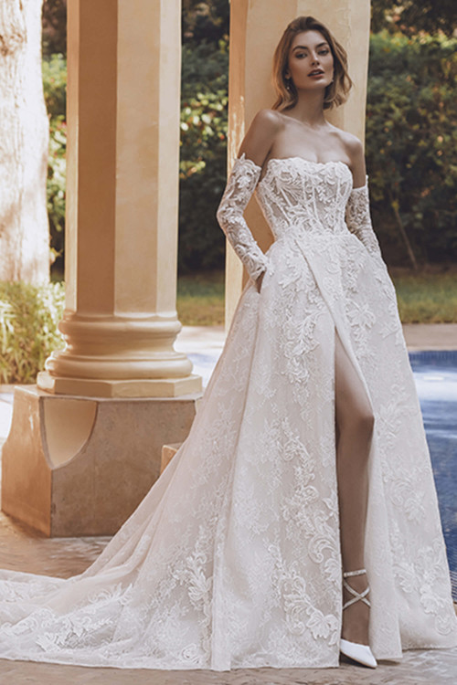Bride in Enzoani Una ball gown with off-the-shoulder sleeves and lace detailing. Bride in Enzoani Una ball gown with off-the-shoulder sleeves and lace detailing.