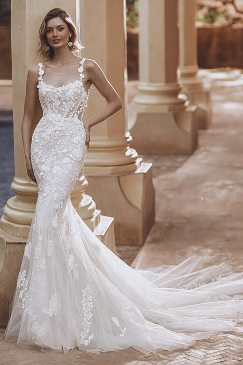 Bride in Enzoani Urmila fit-and-flare gown with scoop neckline and floral straps. Bride in Enzoani Urmila fit-and-flare gown with scoop neckline and floral straps.
