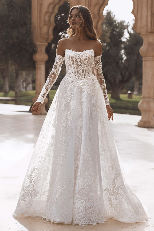 Front view of Enzoani Vanessa gown with scoop neckline, long detachable lace sleeves, and glitter tulle skirt. Front view of Enzoani Vanessa gown with scoop neckline, long detachable lace sleeves, and glitter tulle skirt.