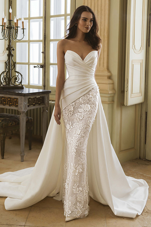 Front view of the ÉLYSÉE Gabby gown with ruched satin bodice, floral lace skirt overlay, and sweetheart neckline. Front view of the ÉLYSÉE Gabby gown with ruched satin bodice, floral lace skirt overlay, and sweetheart neckline.