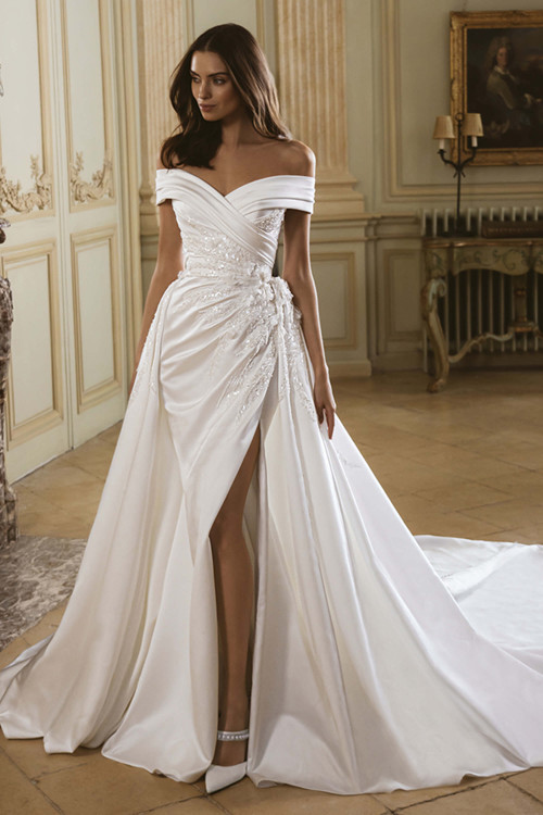 Front view of the ÉLYSÉE Garnet gown with detachable overskirt, off-the-shoulder neckline, and thigh-high slit. Front view of the ÉLYSÉE Garnet gown with detachable overskirt, off-the-shoulder neckline, and thigh-high slit.