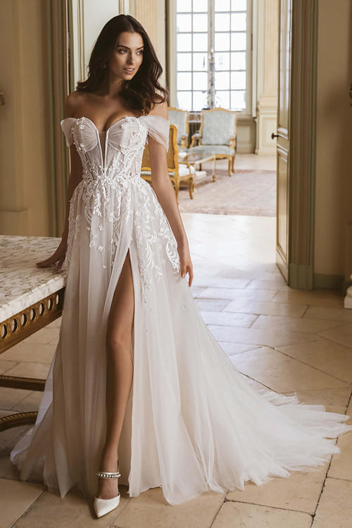 Front view of the ÉLYSÉE Gina A-line wedding gown with plunging sweetheart neckline, corset bodice, and thigh-high slit. Front view of the ÉLYSÉE Gina A-line wedding gown with plunging sweetheart neckline, corset bodice, and thigh-high slit.