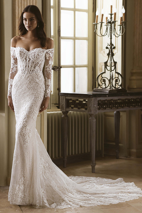 Front view of the ÉLYSÉE Goldie fit-and-flare wedding gown with semi-sweetheart neckline and lace long sleeves. Front view of the ÉLYSÉE Goldie fit-and-flare wedding gown with semi-sweetheart neckline and lace long sleeves.