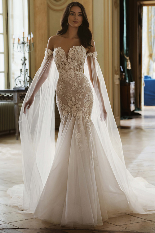 Front view of the ÉLYSÉE Gretchen mermaid wedding gown with sweetheart neckline, 3D floral appliques, and flowing cape sleeves. Front view of the ÉLYSÉE Gretchen mermaid wedding gown with sweetheart neckline, 3D floral appliques, and flowing cape sleeves.