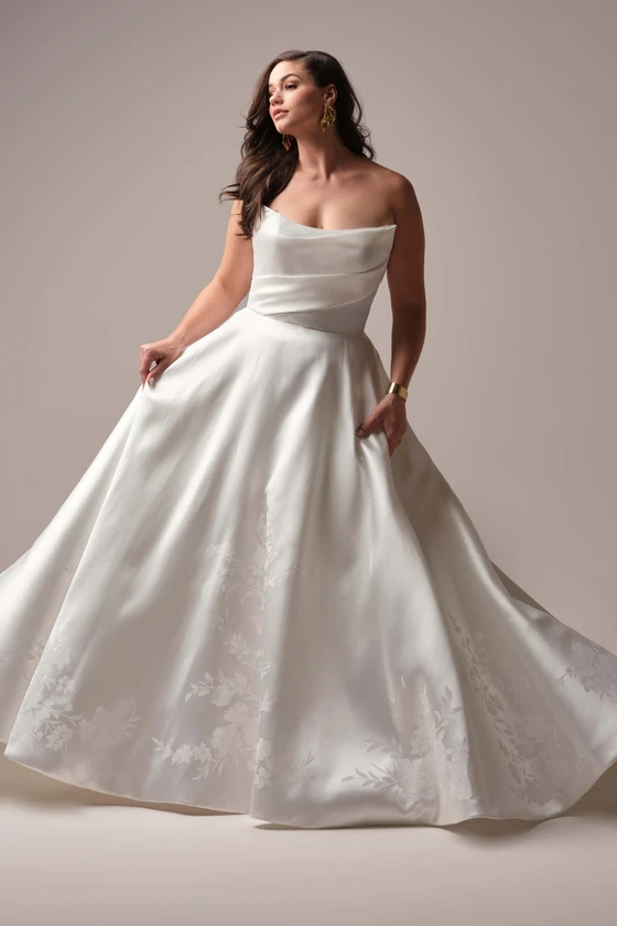 Plus-size bride wearing the Maggie Sottero Radiance A-line gown, highlighting the full satin skirt and unique folded strapless neckline.