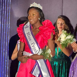 Teen pageant winner in stunning red gown with Miss sash