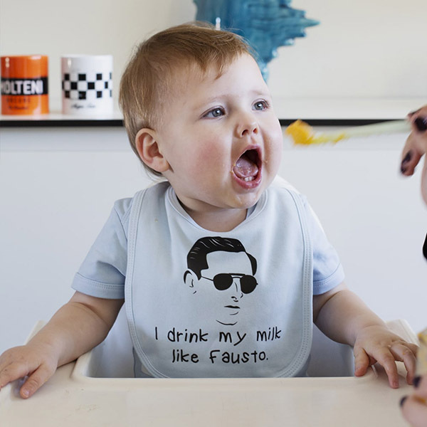 Baby wearing bib with 'I drink my milk like Fausto' design during feeding