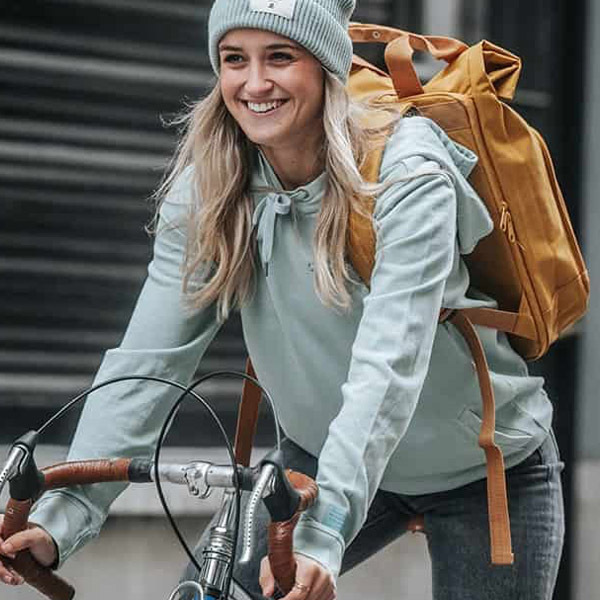 Woman cycling with mustard yellow backpack and casual hoodie, smiling