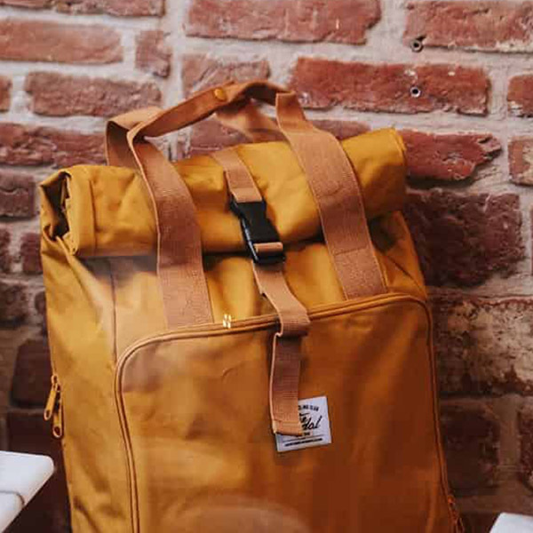 Mustard Yellow backpack against brick wall.