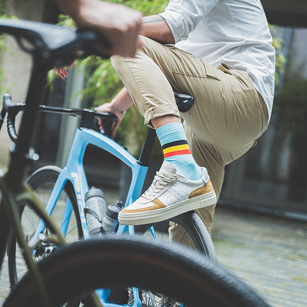 Man in beige pants and striped socks on blue bike.