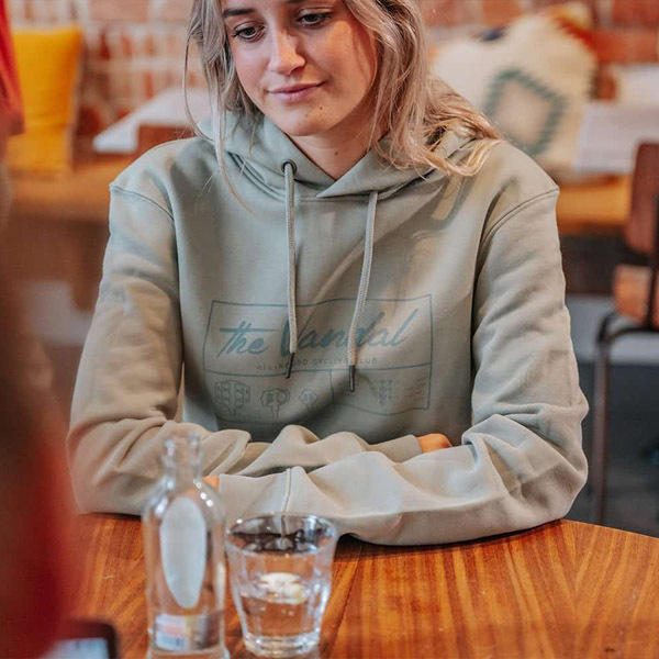 Woman wearing casual hoodie seated at a table in a relaxed cafe setting