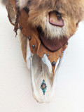 Closeup section of Bison skull wall hanging covered in red coyote fur showing detail of fur, and leather accents with small decorative stones rivets